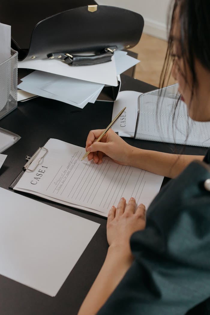 A woman focused on reviewing paperwork at an office desk, capturing a professional working environment.